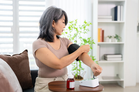 Woman Sitting in living room At Home Measuring Arterial Blood Pressure. healthcare and medical concept