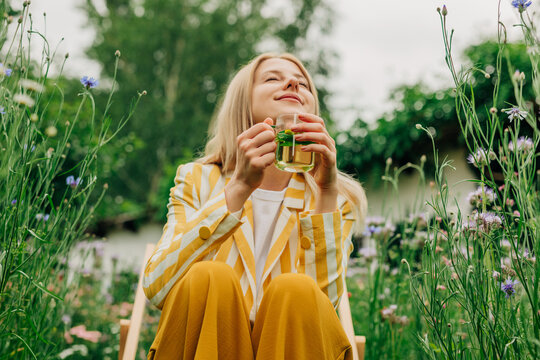 Woman drinks herbal tea in a blooming wildflower garden