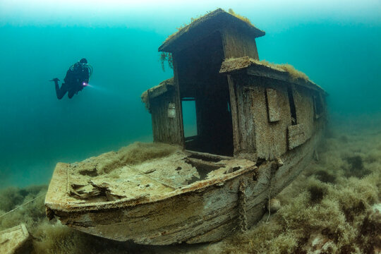 Scuba diver swimming toward shipwreck sunken in Lake Atter