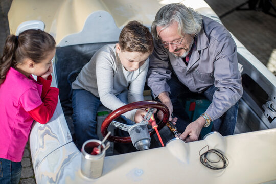 Senior man with boy and girl in a convertible to be restored