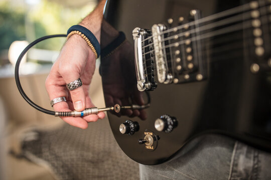 Close-up of man's hand plugging electric guitar