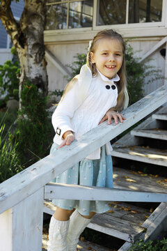 Smiling Girl in Cozy Sweater Enjoying Autumn Day on Wooden Staircase