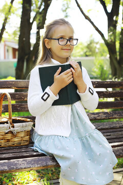 Young Girl Reading on Park Bench with Picnic Basket on a Sunny Day