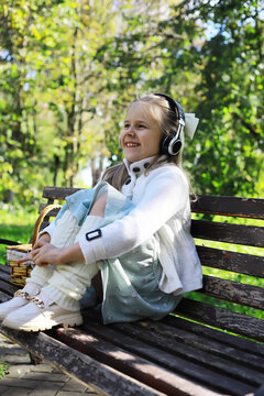 Joyful Young Girl Listening to Music on Park Bench with Headphones