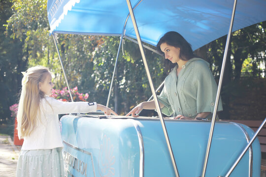 Mother and Daughter Buying Ice Cream at Outdoor Kiosk on a Sunny Day