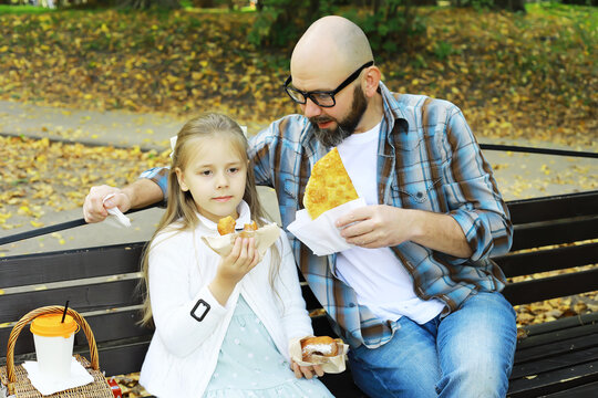 Father and Daughter Enjoying Picnic with Snacks on a Park Bench