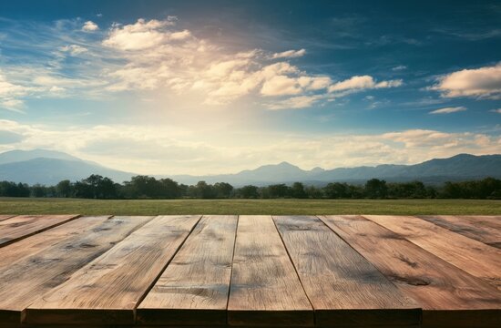 Empty wooden table surface overlooking a scenic landscape with mountains and clouds