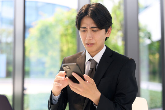 スマホで嫌な通知を見るビジネスマン