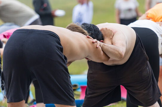 Two men grip each other in a close physical hold