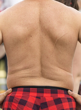 Man stands bare-chested, back visible