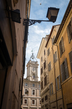 The historic Borromini clock tower framed by narrow city street facades and street lamp in Rome, Italy