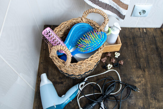 Bathroom Counter Organization with Woven Basket. Hairdryer, towel, curling iron and combs in bathroom at home. Hairpins and hair care and styling items.