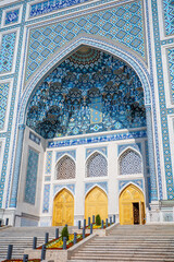 Obraz premium A breathtaking view of an Islamic mosque entrance showcasing exquisite blue mosaic tilework, intricate geometric patterns, Arabic calligraphy, and elegant golden doors