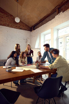 Creative professionals discussing project ideas around conference table in modern office. Concept of collaborative teamwork, project planning, creative decision making and business innovation.