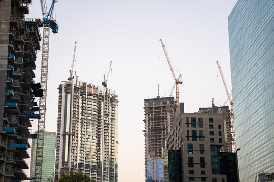 Modern skyscrapers rising in dense urban city skyline, tall glass buildings reflecting sunlight, metropolitan architecture, financial district, and contemporary city development concept.