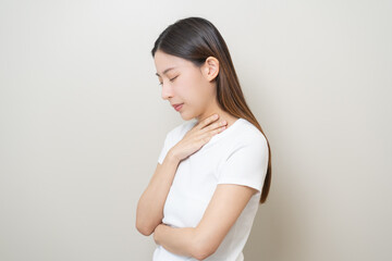 Obraz premium Sickness in inflaming asian young woman, girl use hand check self touch at sore throat, pain thyroid gland on neck or disease reflux, acid of suffer people on wall background. Medical and healthcare.