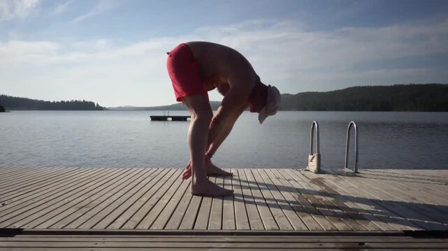 Idre, Sweden A man does morning callisthenics on a wooden pier on the shore of the Osterdalalven River in the Dalarna province in summer.