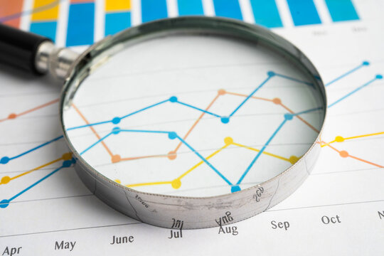 Magnifying glass on data business graphs paper.
