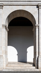 Fototapeta premium Classical stone arches and columns forming a long symmetrical corridor with beautiful light and shadow patterns