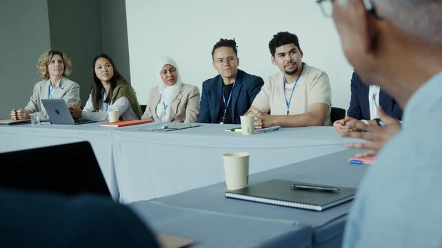 A diverse group of business professionals attends a conference meeting, actively listening to a presentation. Their focused engagement highlights collaboration and teamwork in a corporate environment.