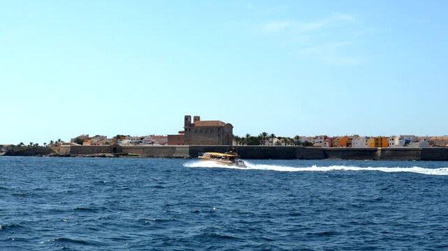 Scenic summer view of a fast tour boat approaching the historic coastline of tabarca island, a popular tourist destination with its fortified walls in the mediterranean sea near alicante