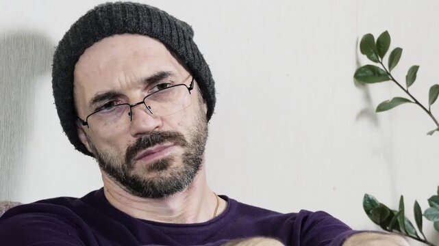 Thoughtful Mature Man in Glasses and Beanie Looking Up in Contemplation