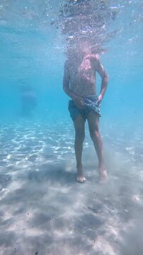 Young boy emerging from the clear turquoise water and smiling at the camera during a beautiful sunny day on tabarca island, an islet in the mediterranean sea, close to alicante, spain