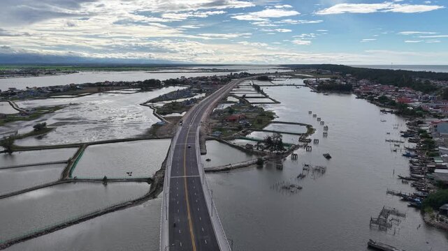 Eye-level drone perspective captures the Thuan An Bridge with the coastal town buildings and harbor visible below, showing the bridge's role connecting communities.