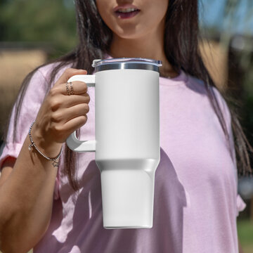 Blank white 40oz tumbler mockup, young woman outdoors, hand close up. Lifestyle scene