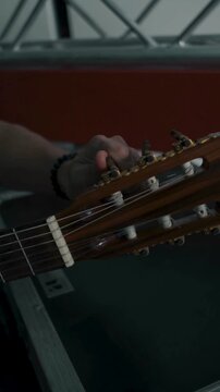 Musician adjusting nylon string guitar tuning pegs before studio performance session