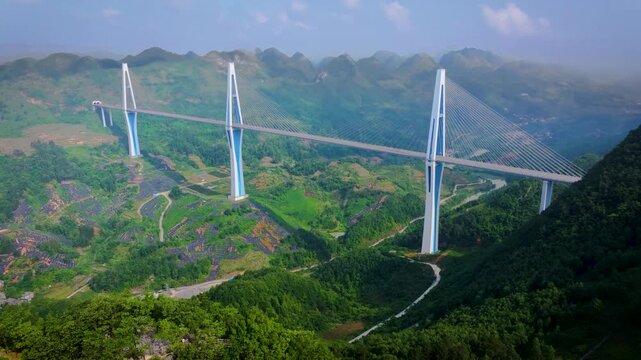 Aerial view of a massive highway cable-stayed bridge over a deep mountain valley