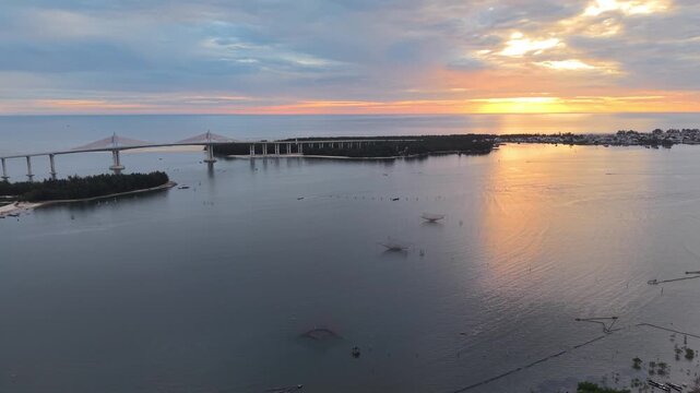 Serene sunset aerial captures circular fish cages on the calm lagoon waters near Hue, with the warm sky colors reflected on the still water surface.