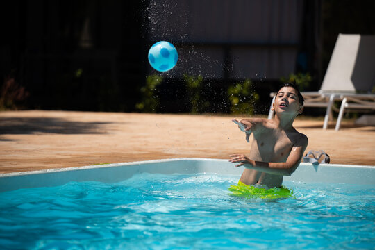 Boy playing with ball in swimming pool during summer vacation