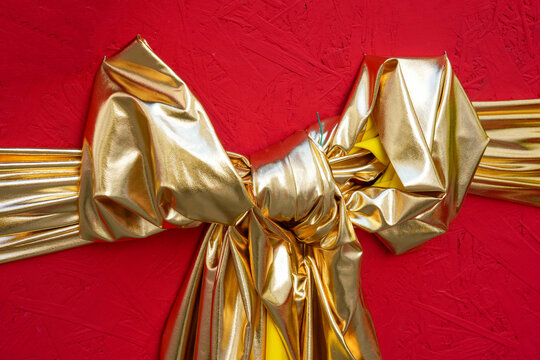 Oversized gold gift bow on a red background