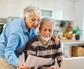 Senior couple checking bills and calculating expenses using a laptop at home, debt taxes concept, worried married elderly couple © Lumos sp