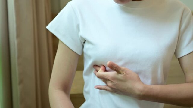 Cropped shot view of young Asian woman touching her breast for checking breast size or cancer awareness.