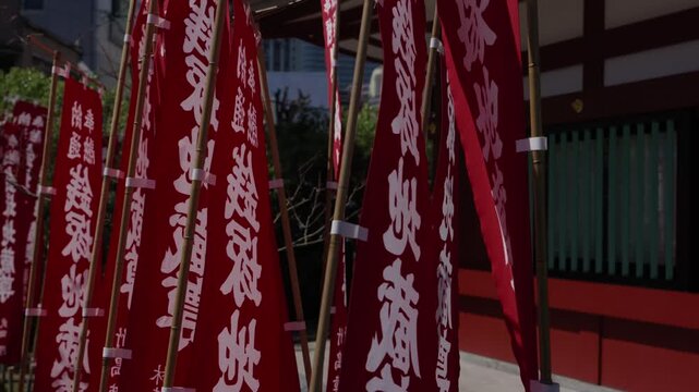 Rows of red nobori banners with white Japanese calligraphy lining a Buddhist temple entrance in Japan