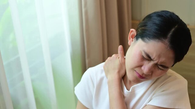 Cropped shot view of Asian woman having shoulder and neck pain from working longtime. Shoulder pain is when rotator cuff tendons become inflamed or trapped in your shoulder.