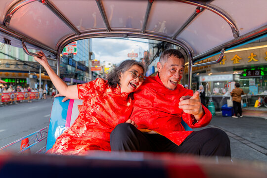 Couple enjoys ride in tuk-tuk during festive celebration in city streets