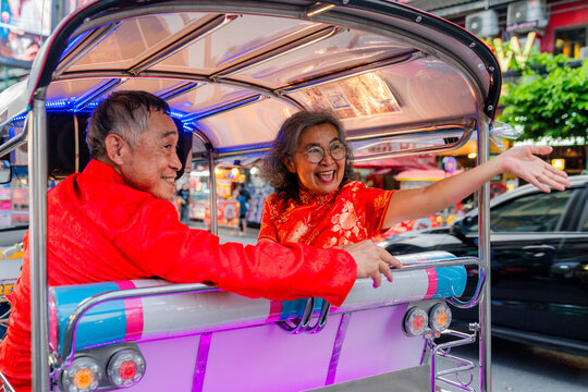 Couple enjoys ride in tuk-tuk during busy evening in Bangkok street