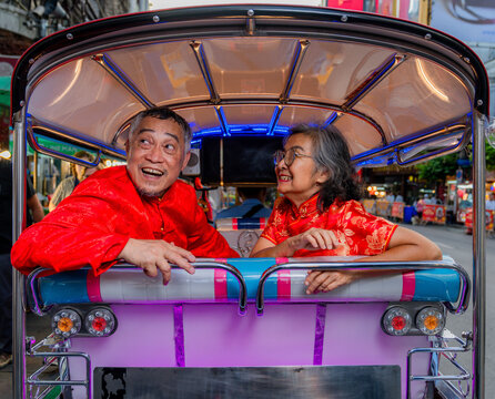 Couple enjoys tuk-tuk ride in Bangkok while smiling and exploring the local street scenes