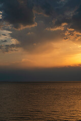 Fototapeta premium A serene and minimalist view of Lake Constance (Bodensee) at sunset, seen from the Austrian shore in Bregenz, Vorarlberg, featuring warm golden reflections on calm water beneath a soft, dramatic sky.