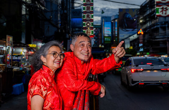 Couple wearing bright red outfits enjoy a lively street scene in the evening
