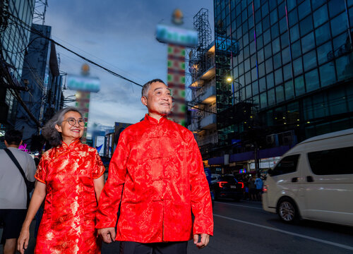 Couple walks hand in hand during a festival celebration in the city with bright lights at dusk