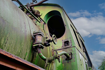 Low angle view of a rusty green vintage steam locomotive against blue sky © Констянтин Батыльчук