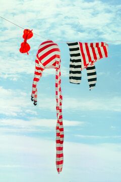 Vibrant red and white striped swimsuit and heart-shaped sunglasses hanging on clothesline against a blue sky