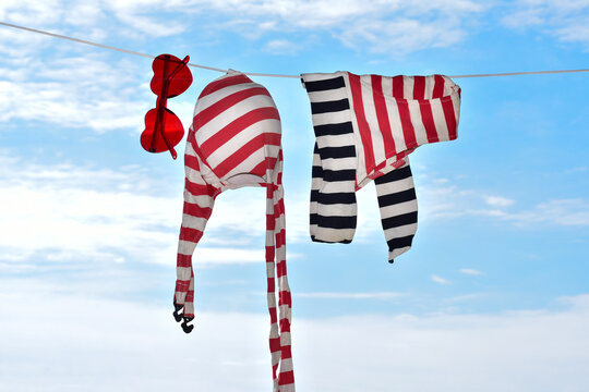 Red and white striped swimsuit and heart-shaped sunglasses hanging on clothesline