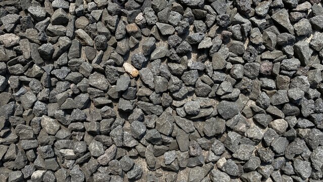 Top view of dark gray crushed gravel stones and macadam texture