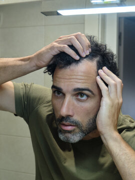 Man checking hair loss in bathroom mirror