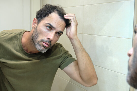 Man checking hair loss in bathroom mirror